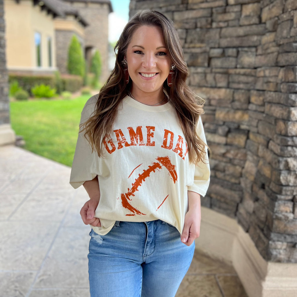Ivory oversized crop graphic tee with burnout orange football outline and gameday wording. 