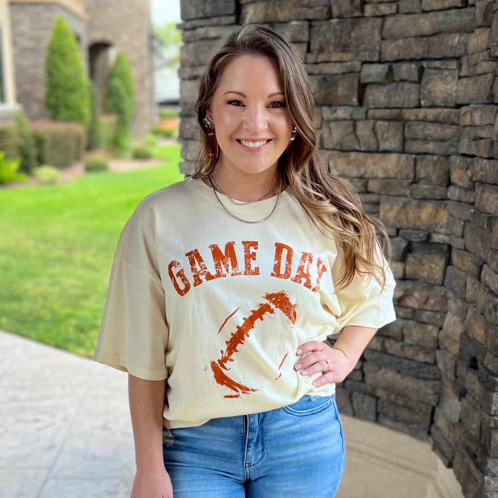 Ivory oversized crop graphic tee with burnout orange football outline and gameday wording. 
